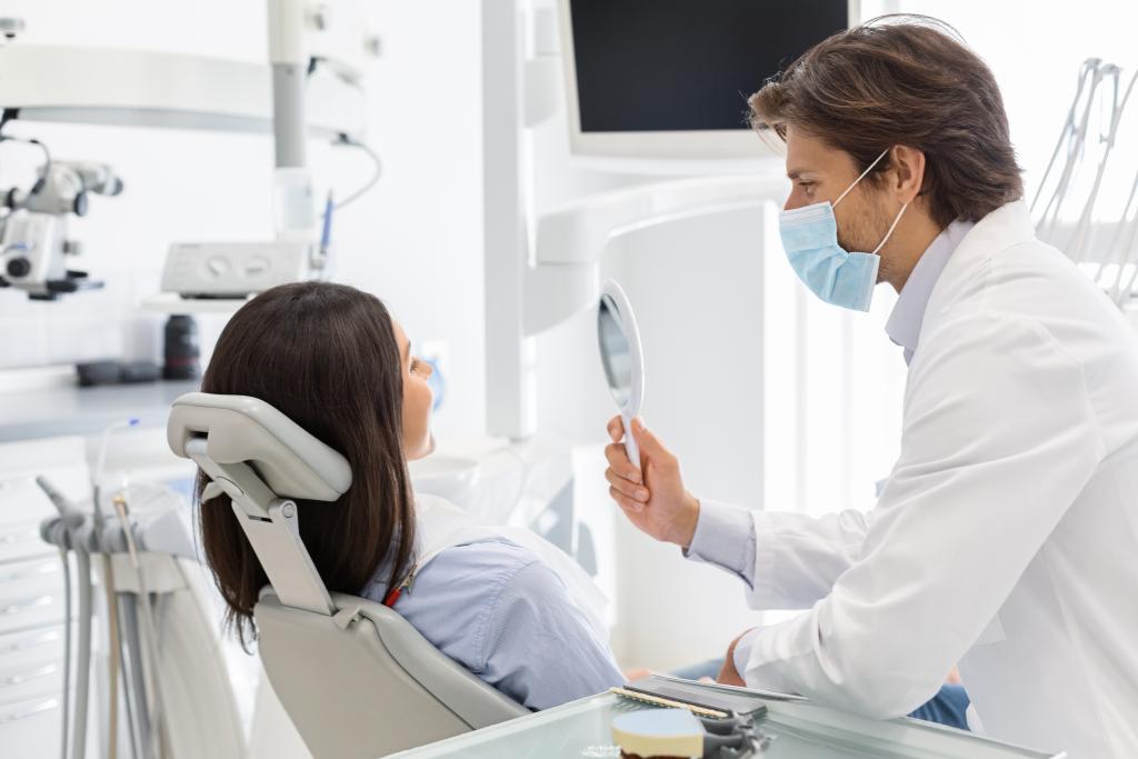 Dentist showing female patient mirror to check new smile